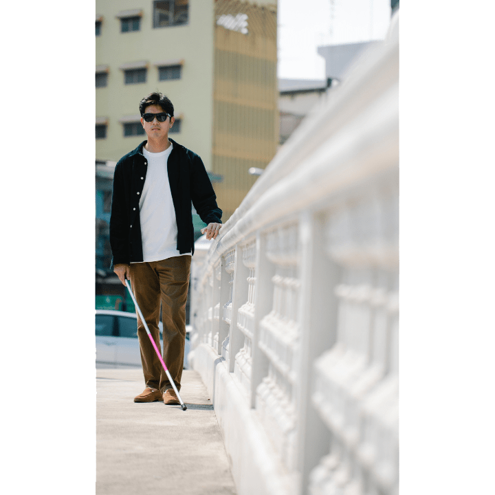 jeune homme aveugle qui marche sur un pont avec des immeubles en fond